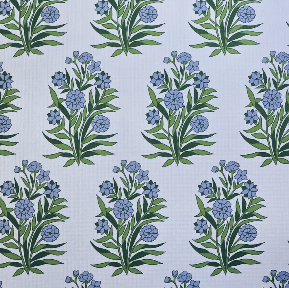 Detail of fabric in a repeating floral print in shades of blue and green on a light blue field.