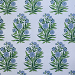 Detail of fabric in a repeating floral print in shades of blue and green on a light blue field.