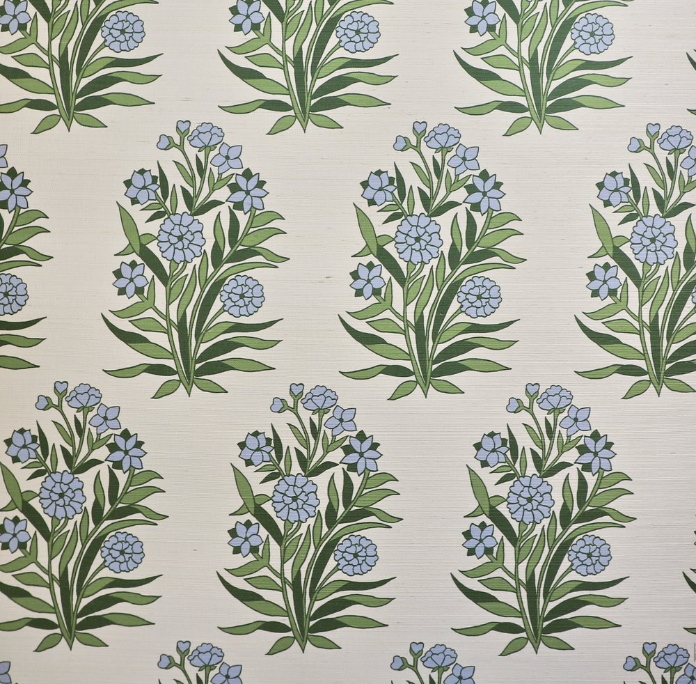 Detail of fabric in a repeating floral print in shades of blue and green on a cream field.