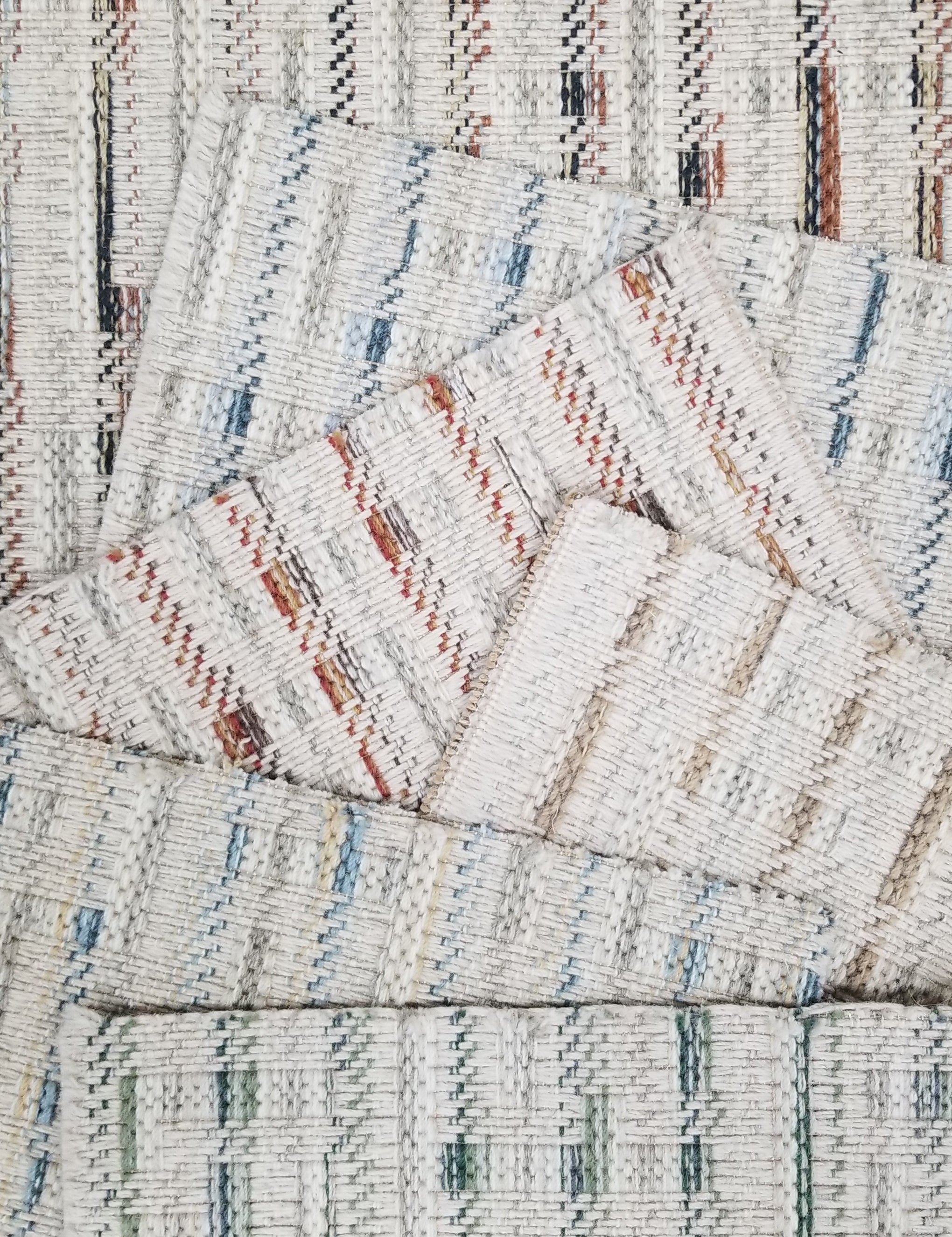 Broadloom carpet samples with textural stripes on a cream ground in a range of colors. 