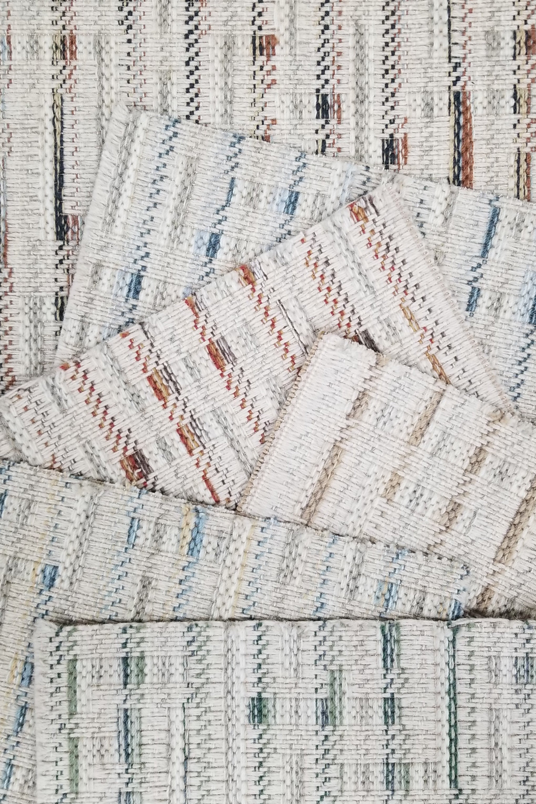 Broadloom carpet samples with textural stripes on a cream ground in a range of colors. 