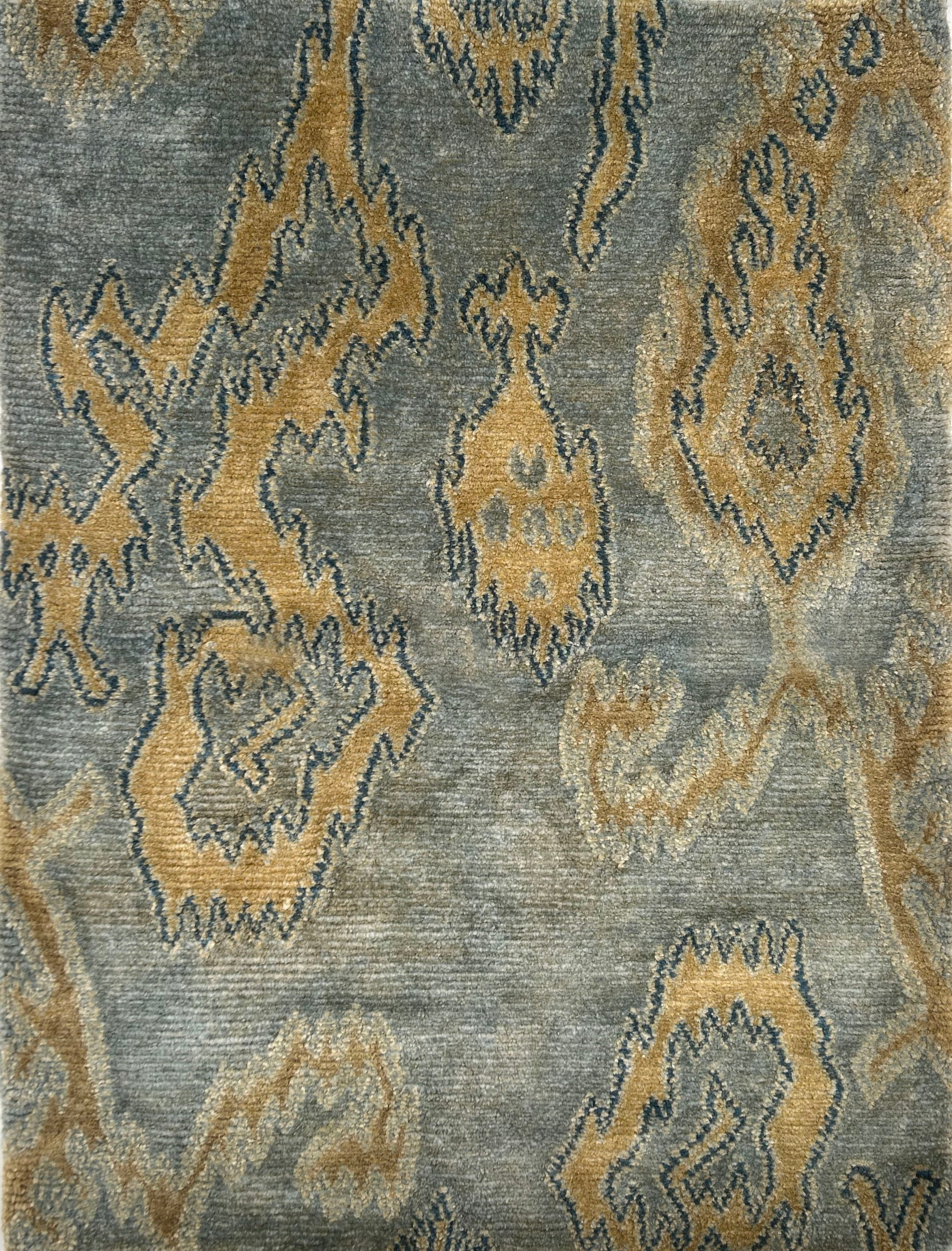 Handknotted rug in an abstract ikat design in tan on a blue-grey field