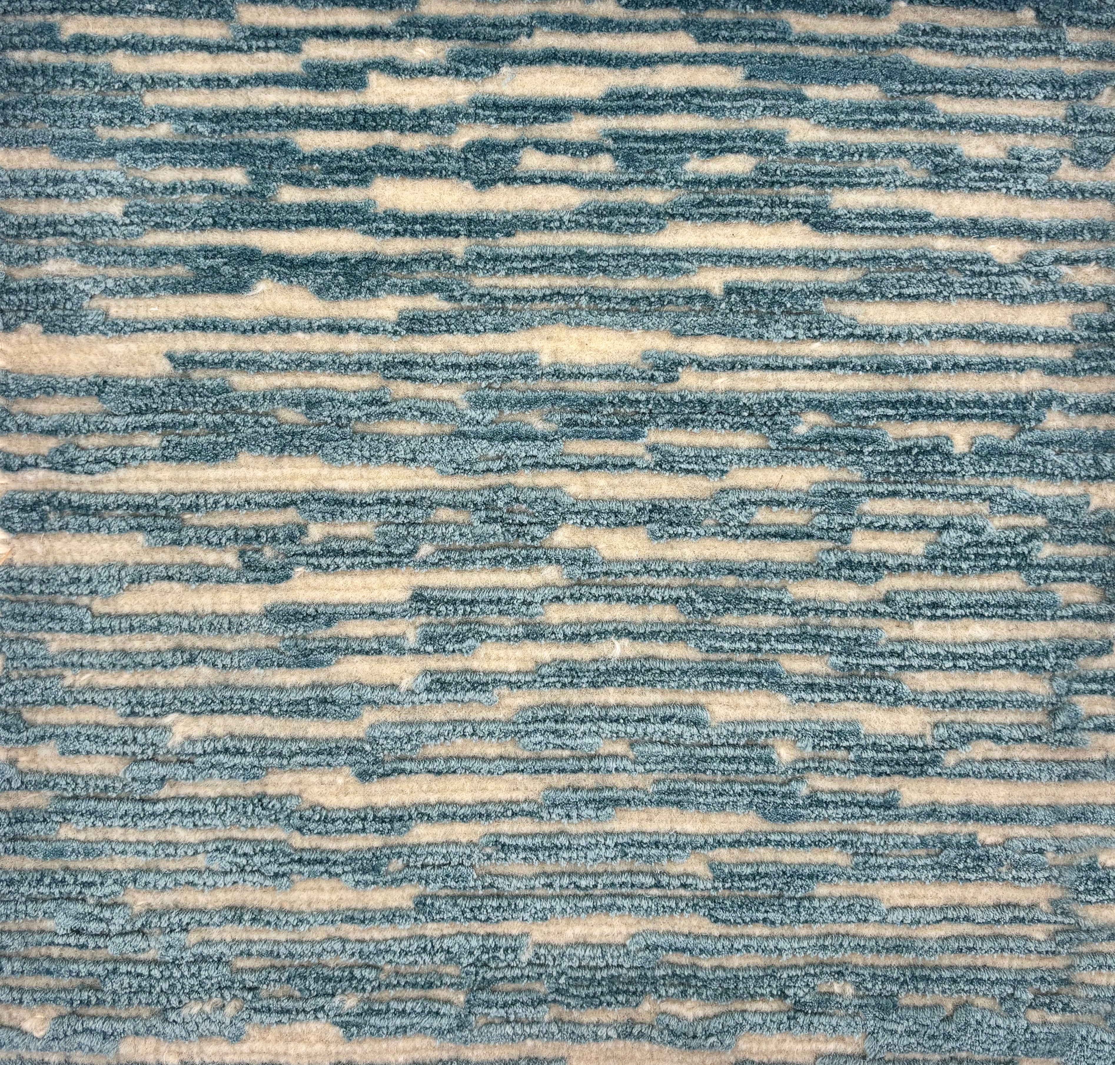 Handknotted rug sample in a textural linear design in turquoise on a cream field.