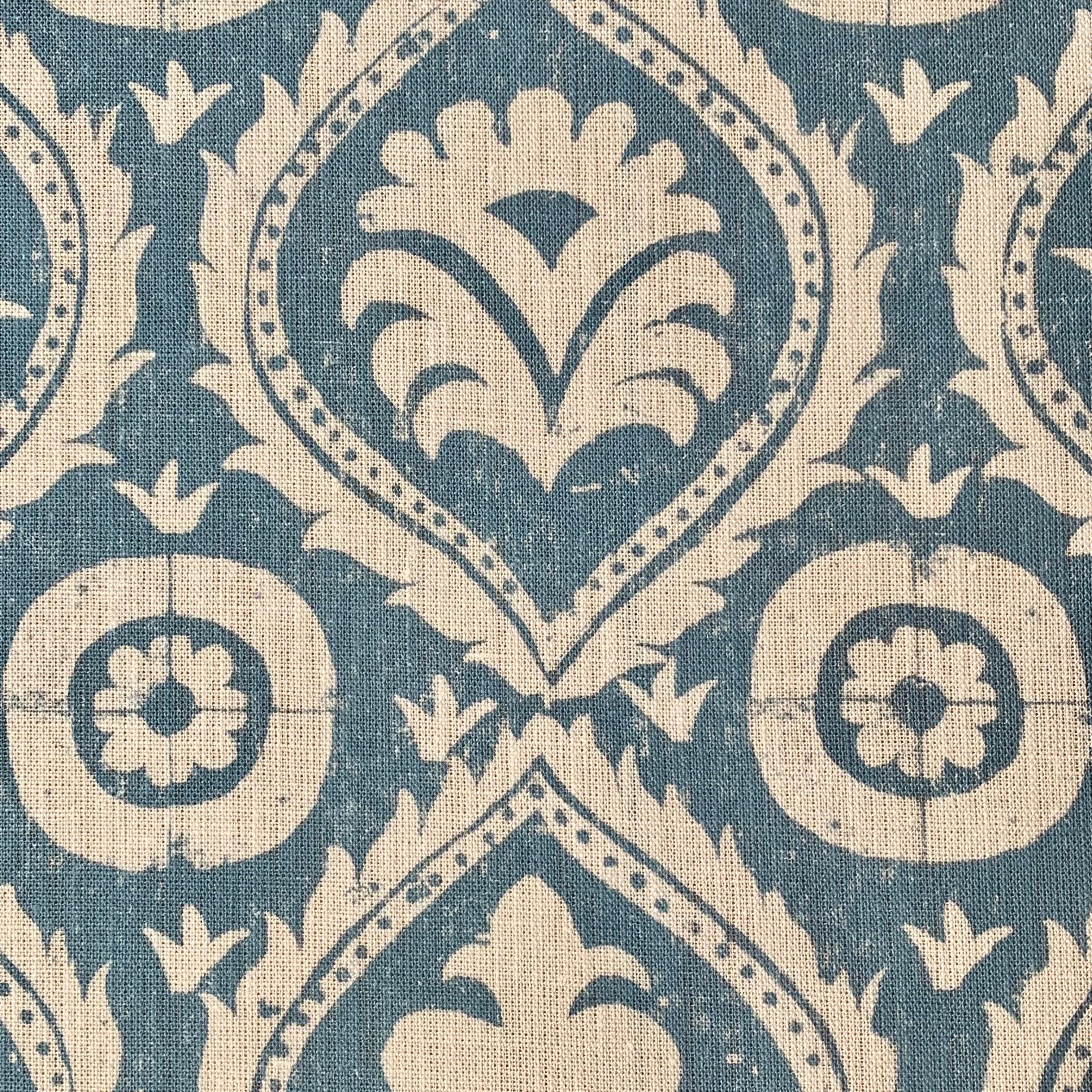 Close-up of fabric in a floral damask print in tan on a blue field.