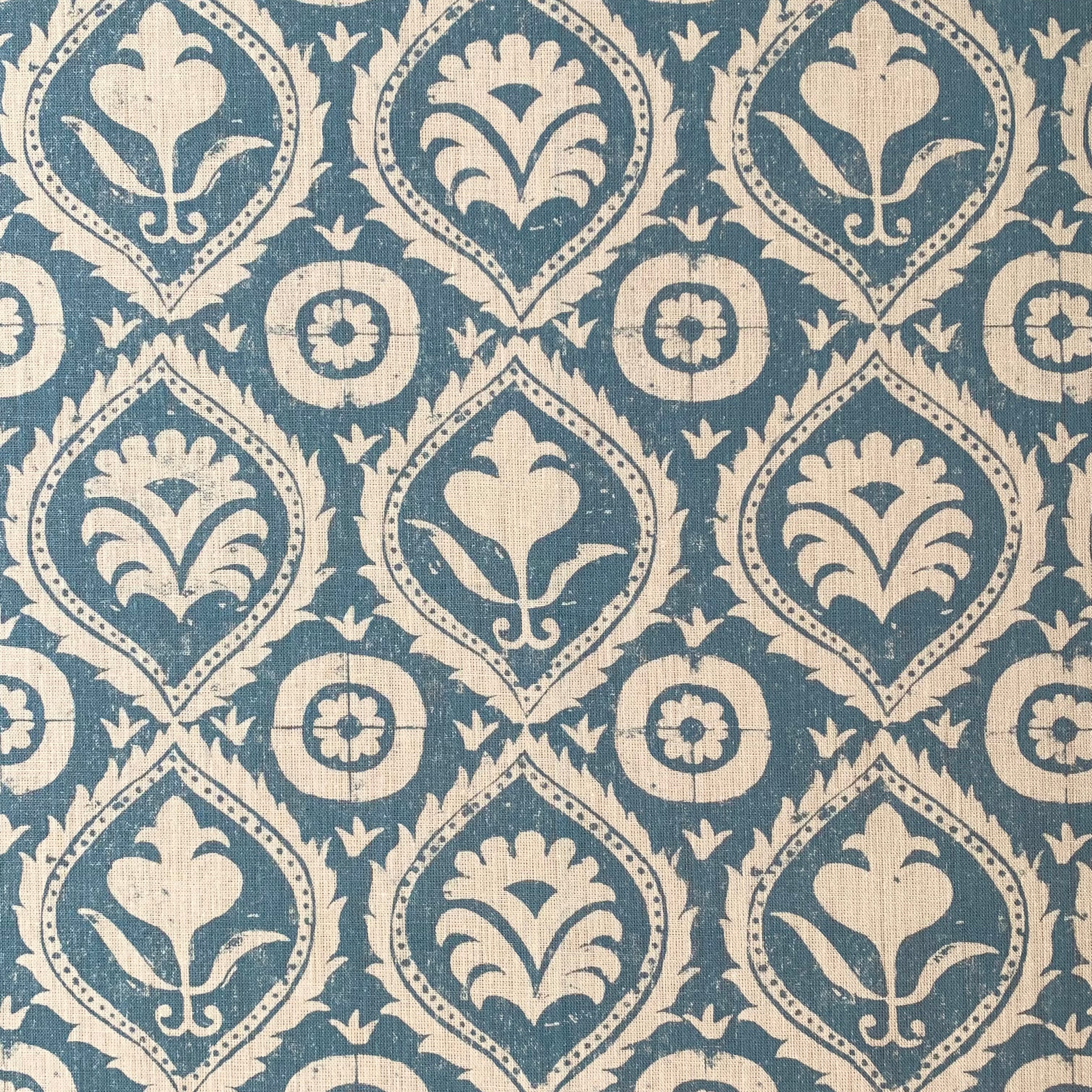 Detail of fabric in a floral damask print in tan on a blue field.