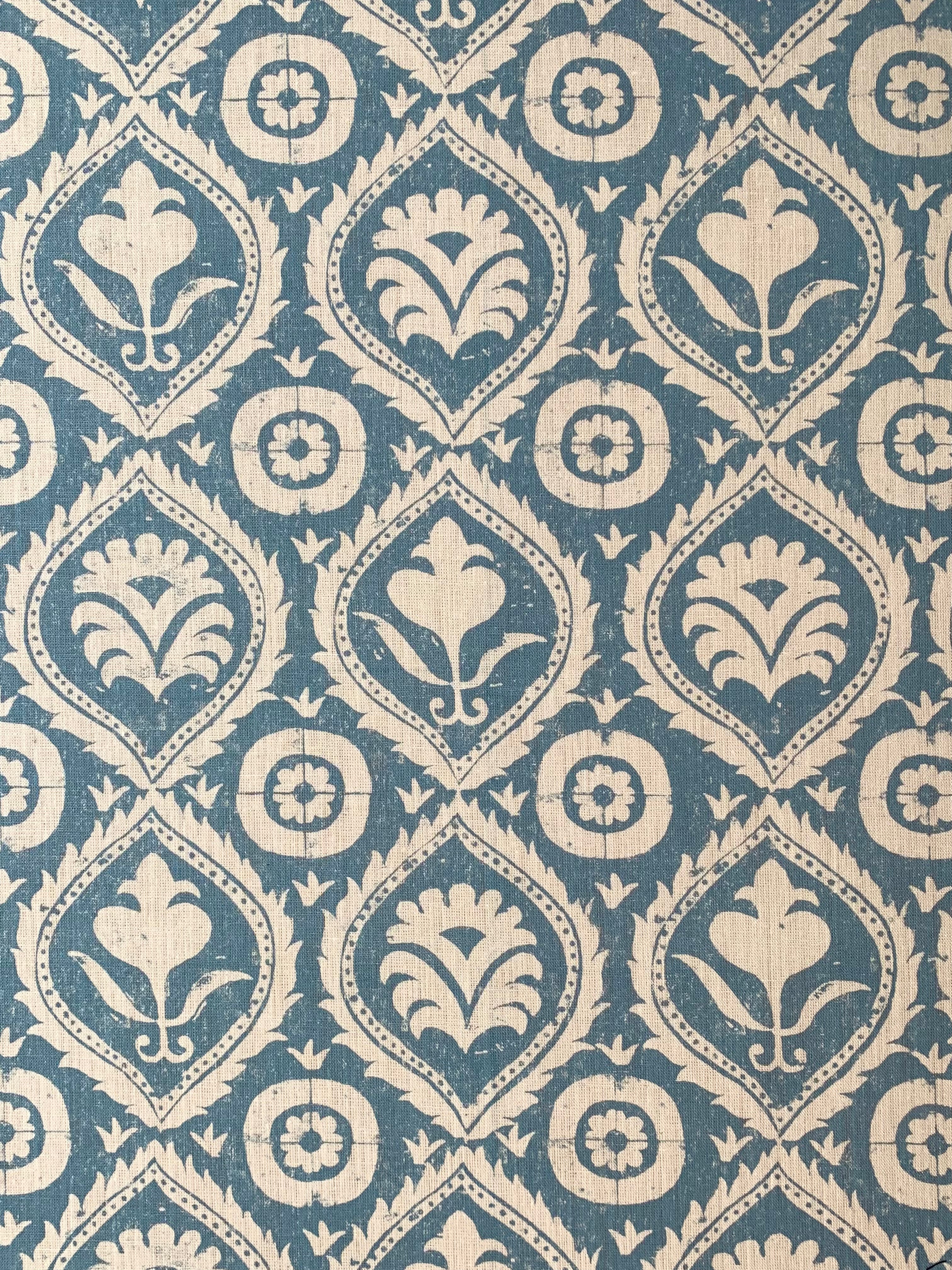 Detail of fabric in a floral damask print in tan on a blue field.