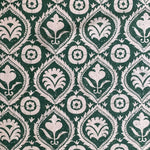 Detail of fabric in a floral damask print in white on a dark green field.