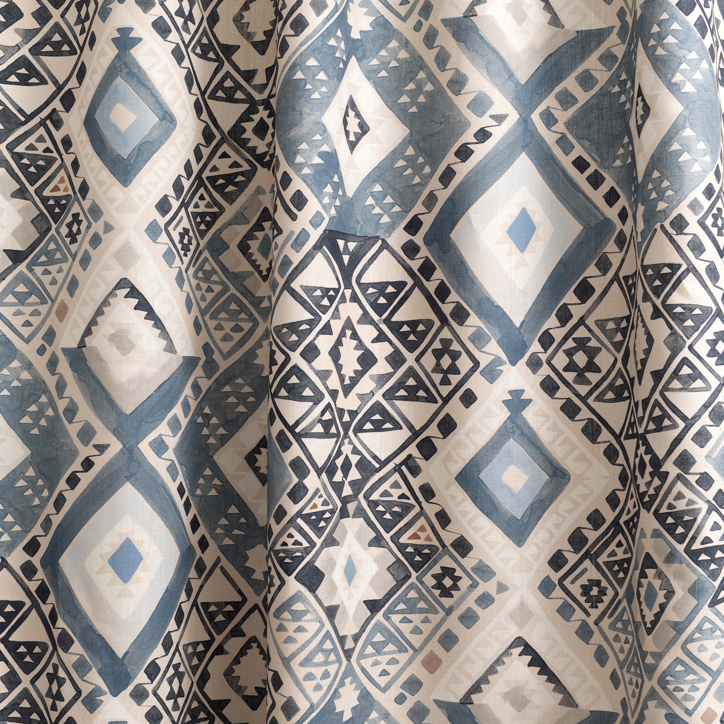 Draped fabric yardage in a painterly diamond print in shades of blue, tan and gray.