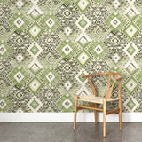 A wooden chair stands in front of a wall papered in a painterly diamond print in shades of green, gray and white.