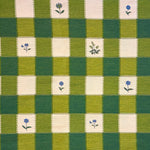 Green and cream checkered fabric with small floral patterns in selected squared