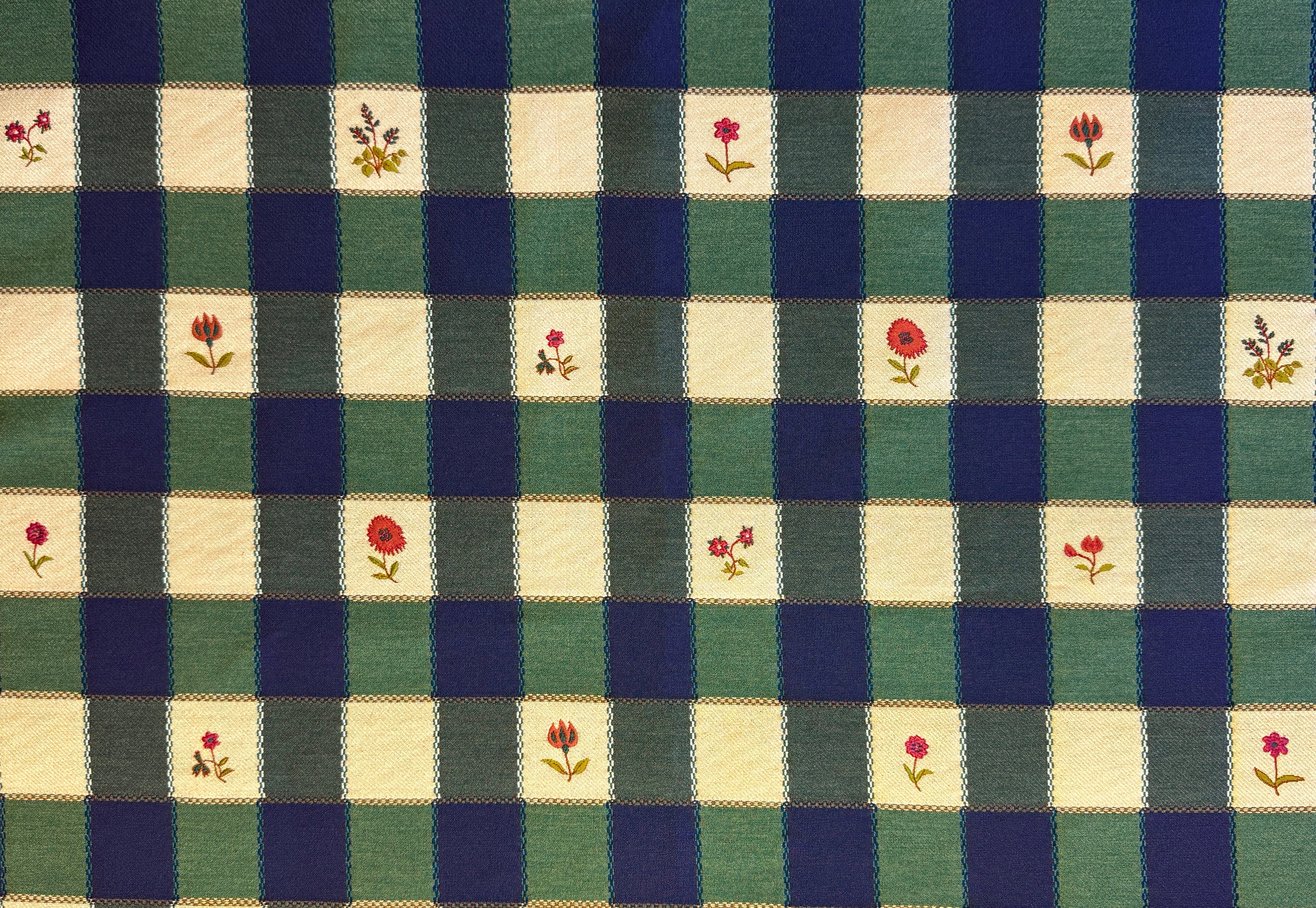 Checkered fabric pattern with floral accents in green, blue, and beige.