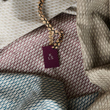 Draped fabrics in repeating abstract prints in various blue, maroon and tan colorways, with a tag labeled "KLS" on top.
