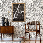 A midcentury inspired living room with a wall papered in a painterly botanical print in black on a white field.