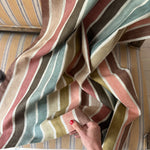 Striped fabric with a hand touching it, on a striped sofa