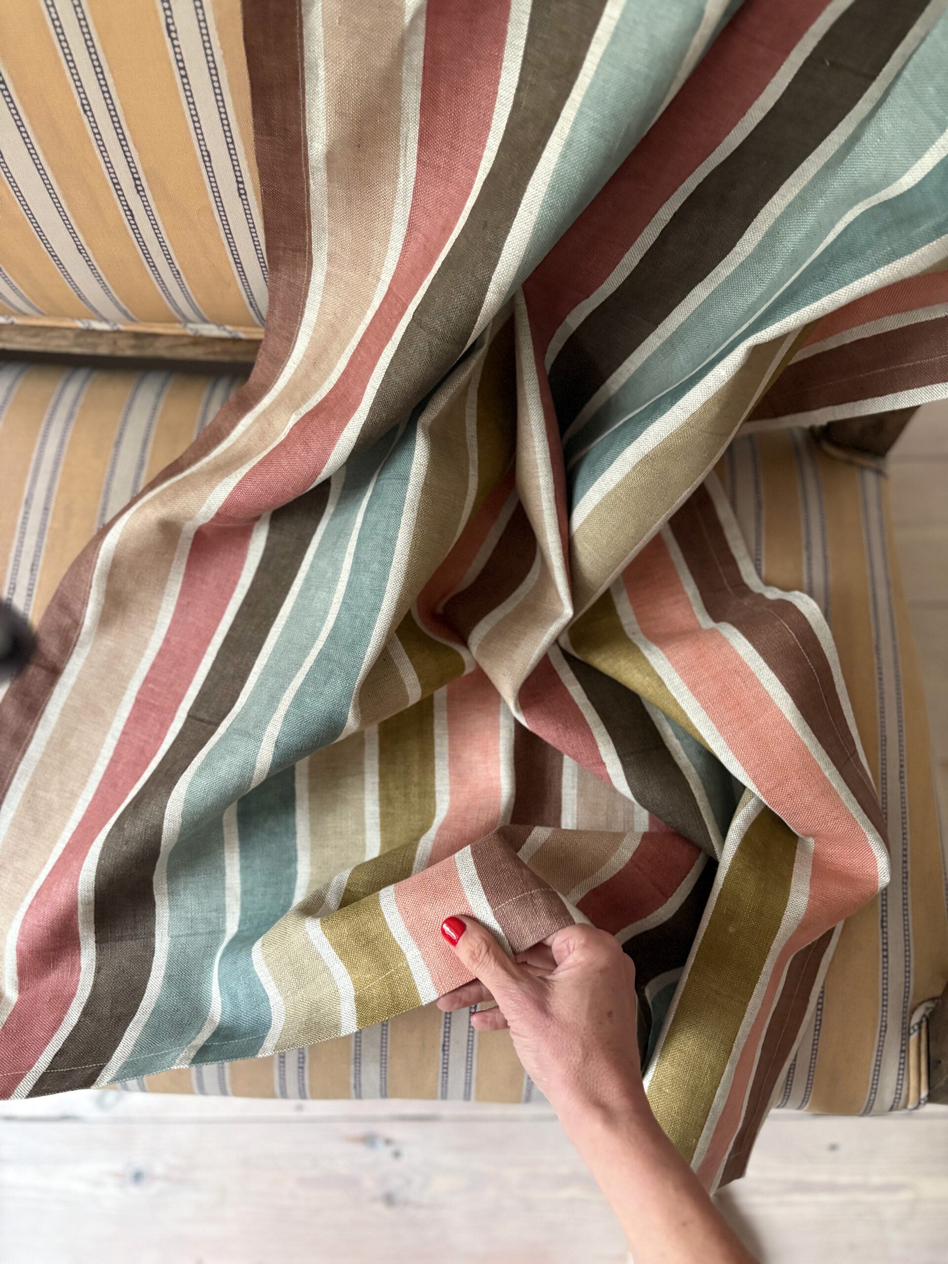 Striped fabric with a hand touching it, on a striped sofa