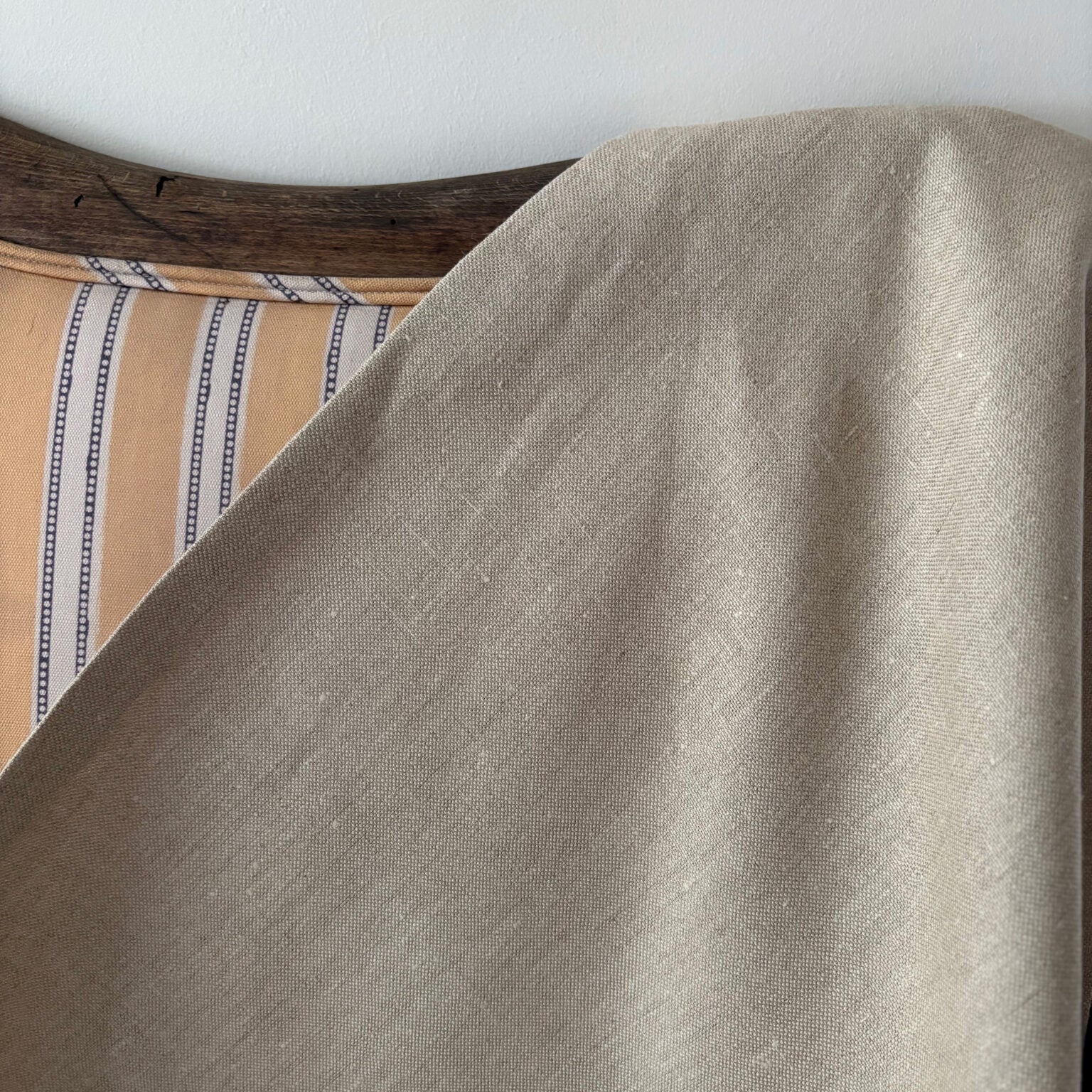 Close-up of a beige fabric draped over a yellow striped sofa.