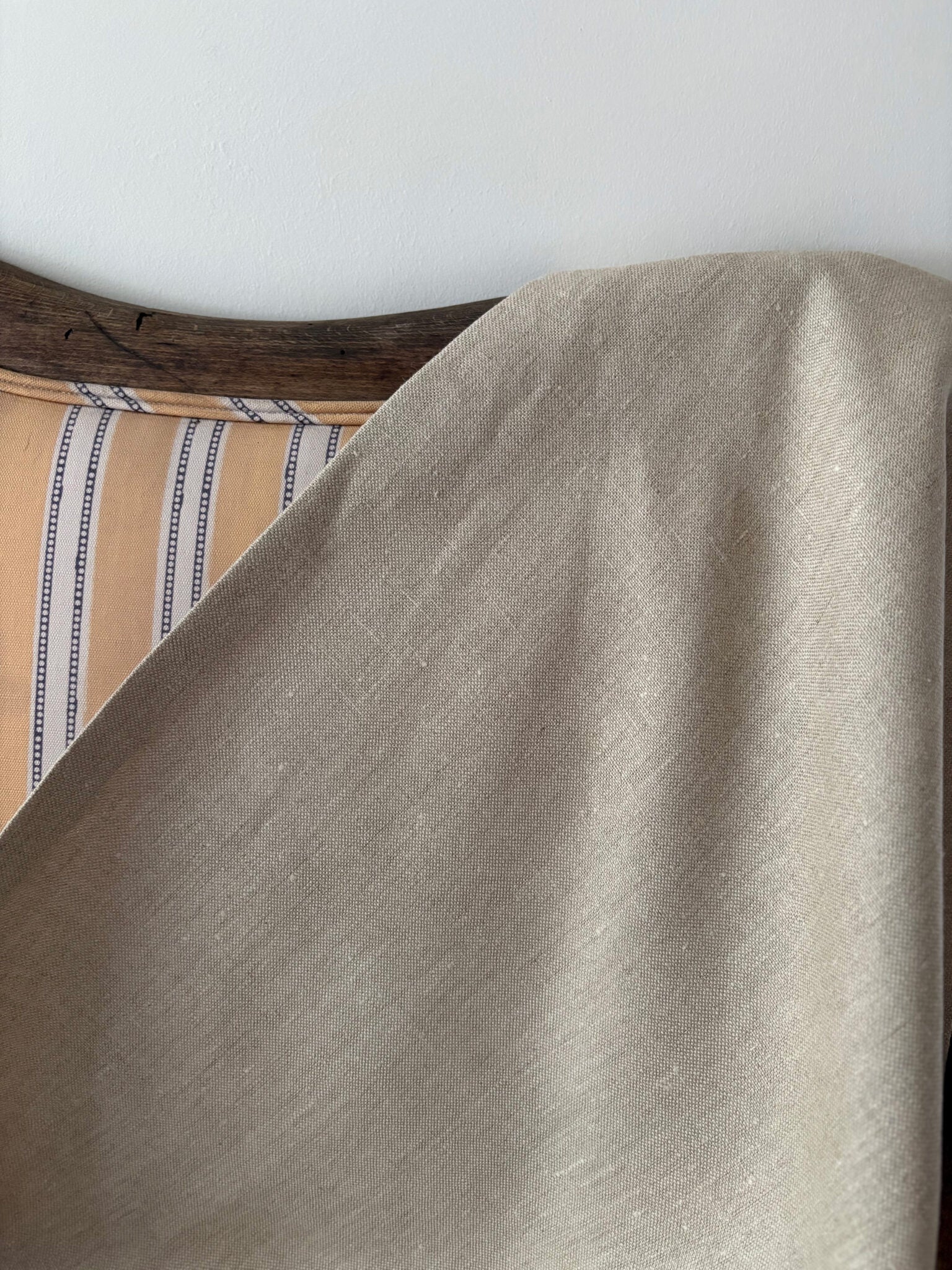 Close-up of a beige fabric draped over a yellow striped sofa.