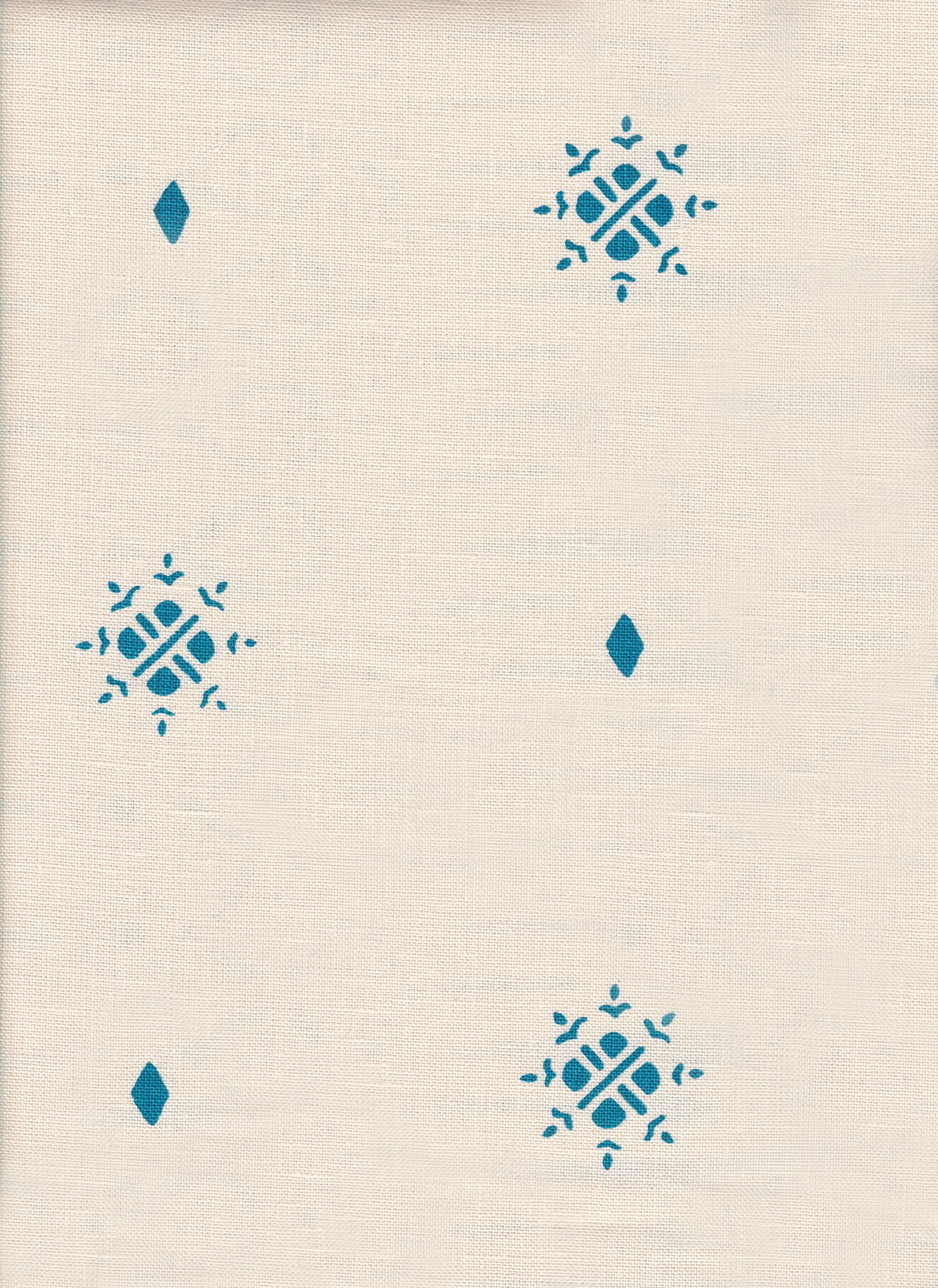 Detail of fabric in a repeating geometric starburst print in turquoise on a cream field.