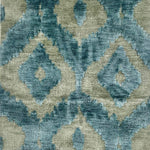 A green and turquoise silk rug woven in an ikat geometric pattern.