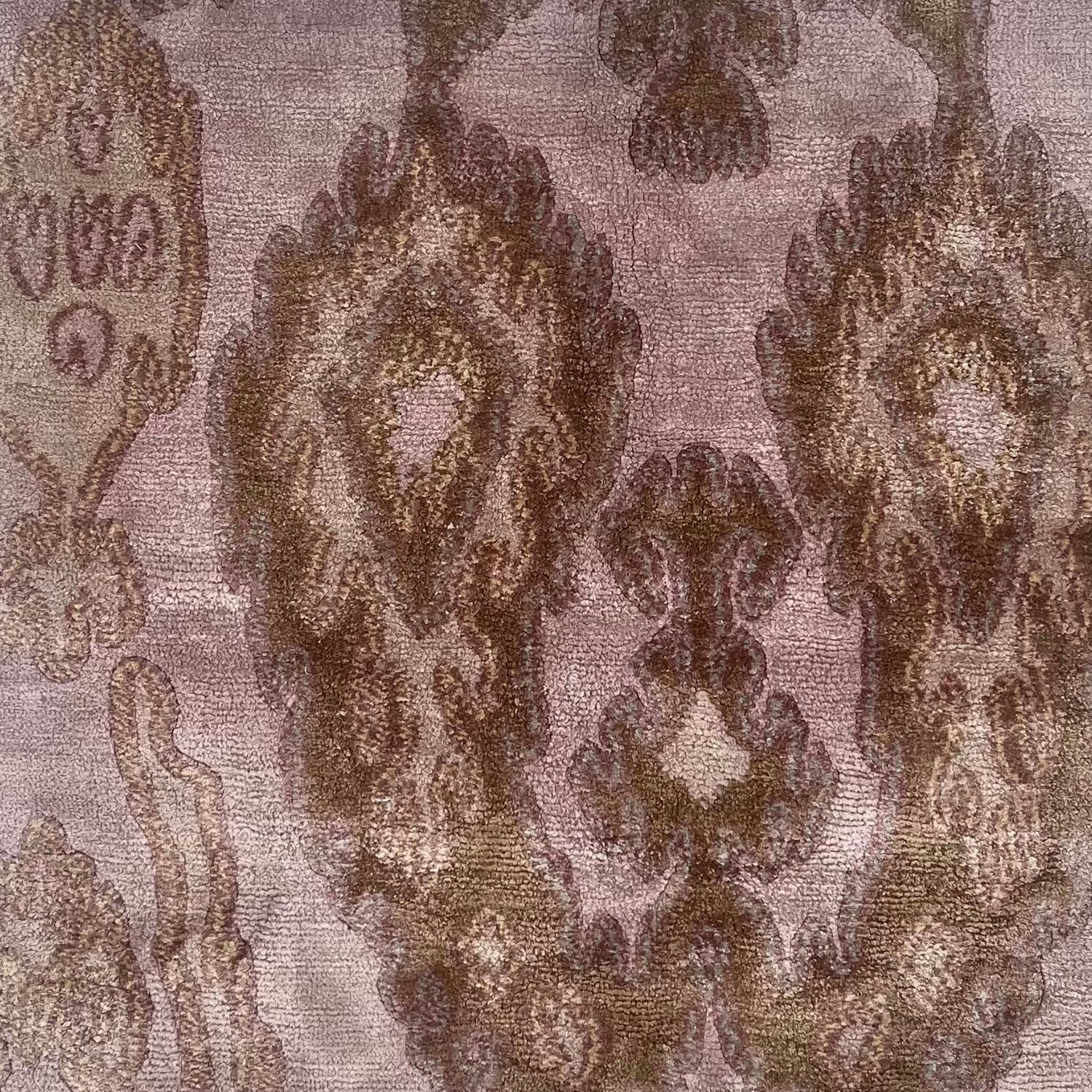 A handknotted rug with an ikat inspired motif in lavender and tan.