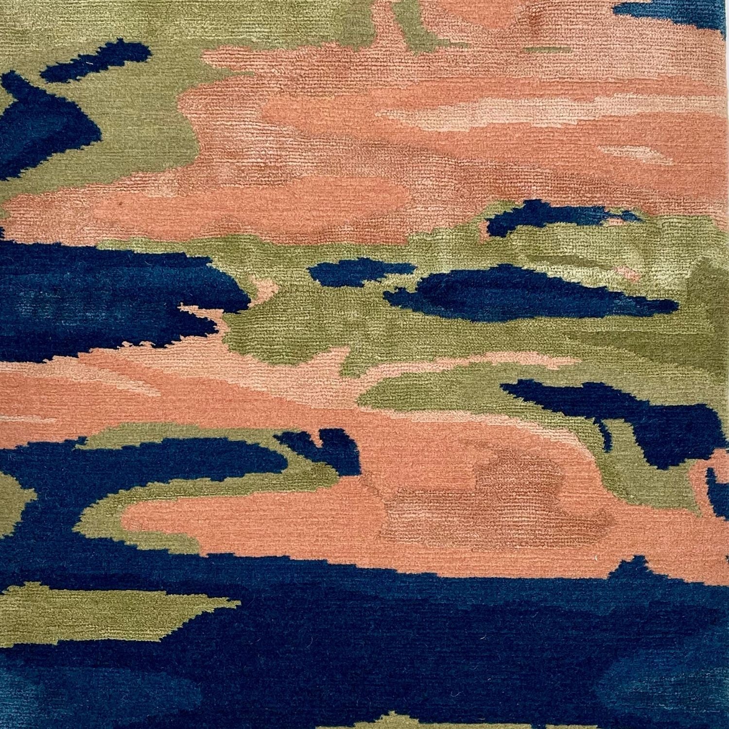 A silk rug with organic shapes in dark blue, peach and green.