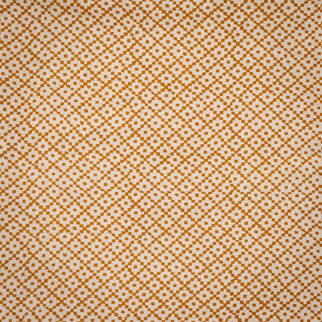 Detail of fabric in a diamond lattice print in orange on a cream field.