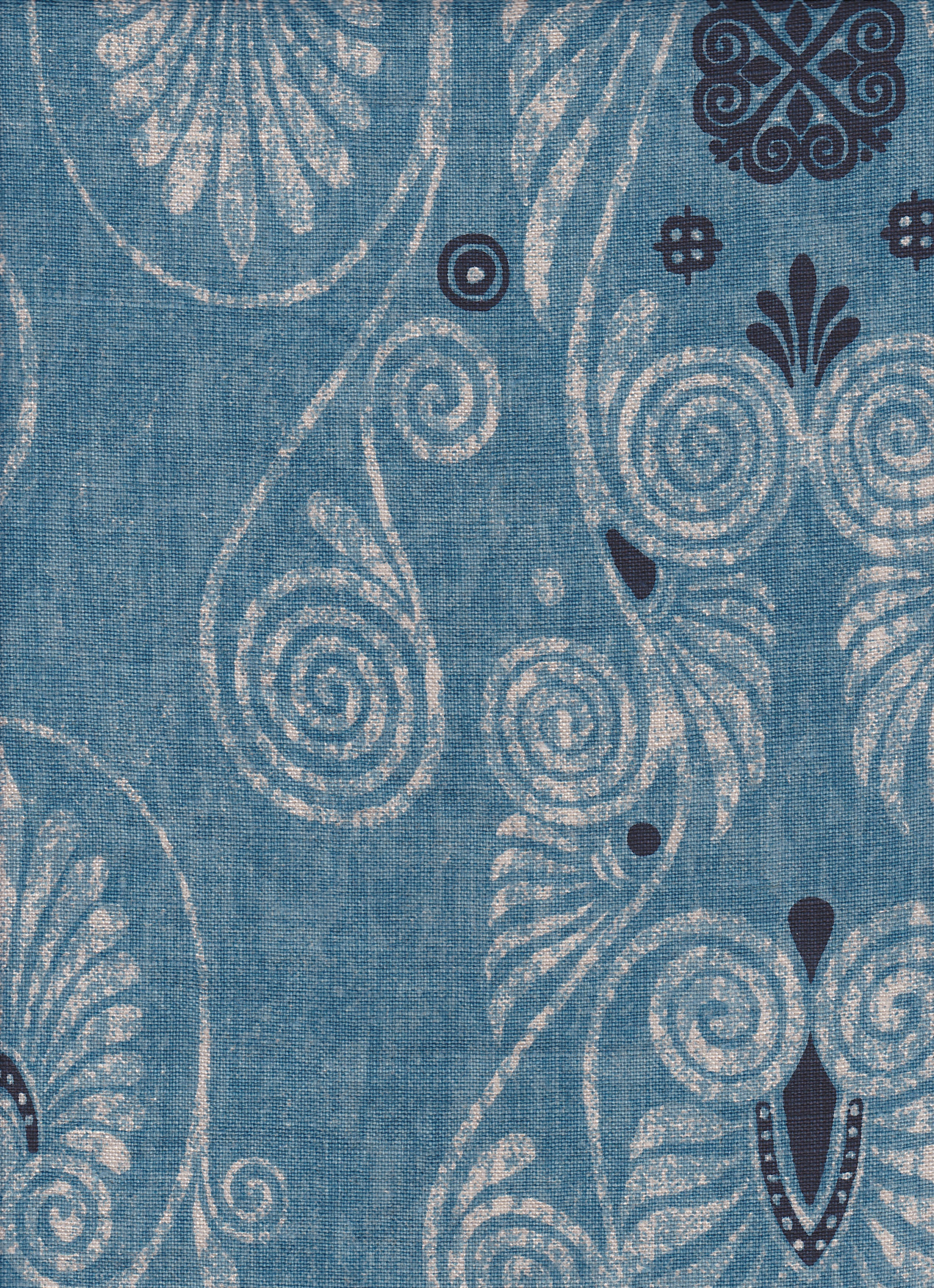 Detail of fabric in a damask print in shades of tan and navy on a blue field.