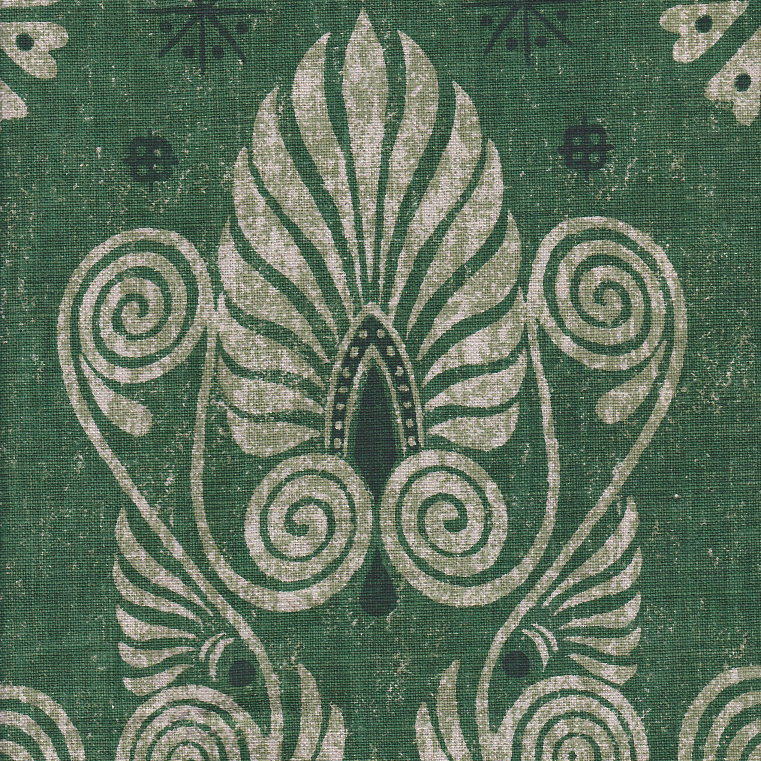 Detail of fabric in a damask print in shades of dark green and cream on a green field.