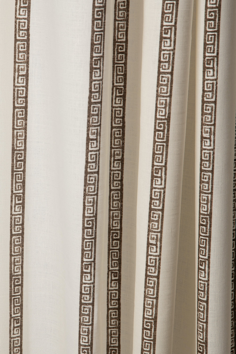 Draped printed fabric in a minimal geometric linear pattern in brown on a cream field.