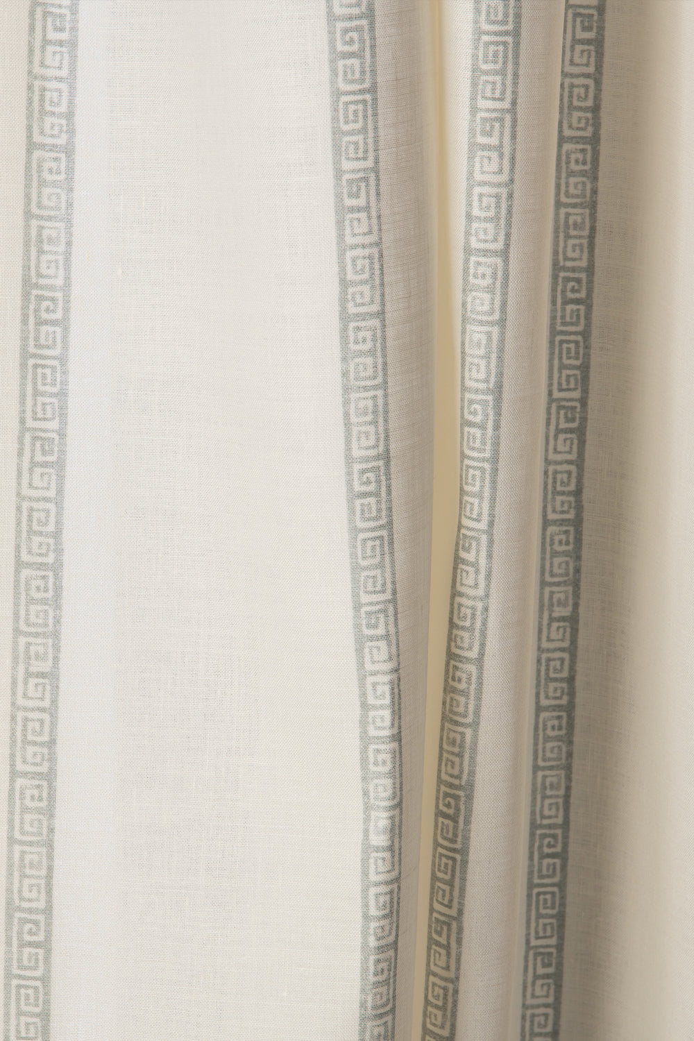 Draped printed fabric in a minimal geometric linear pattern in dusty blue on a cream field.