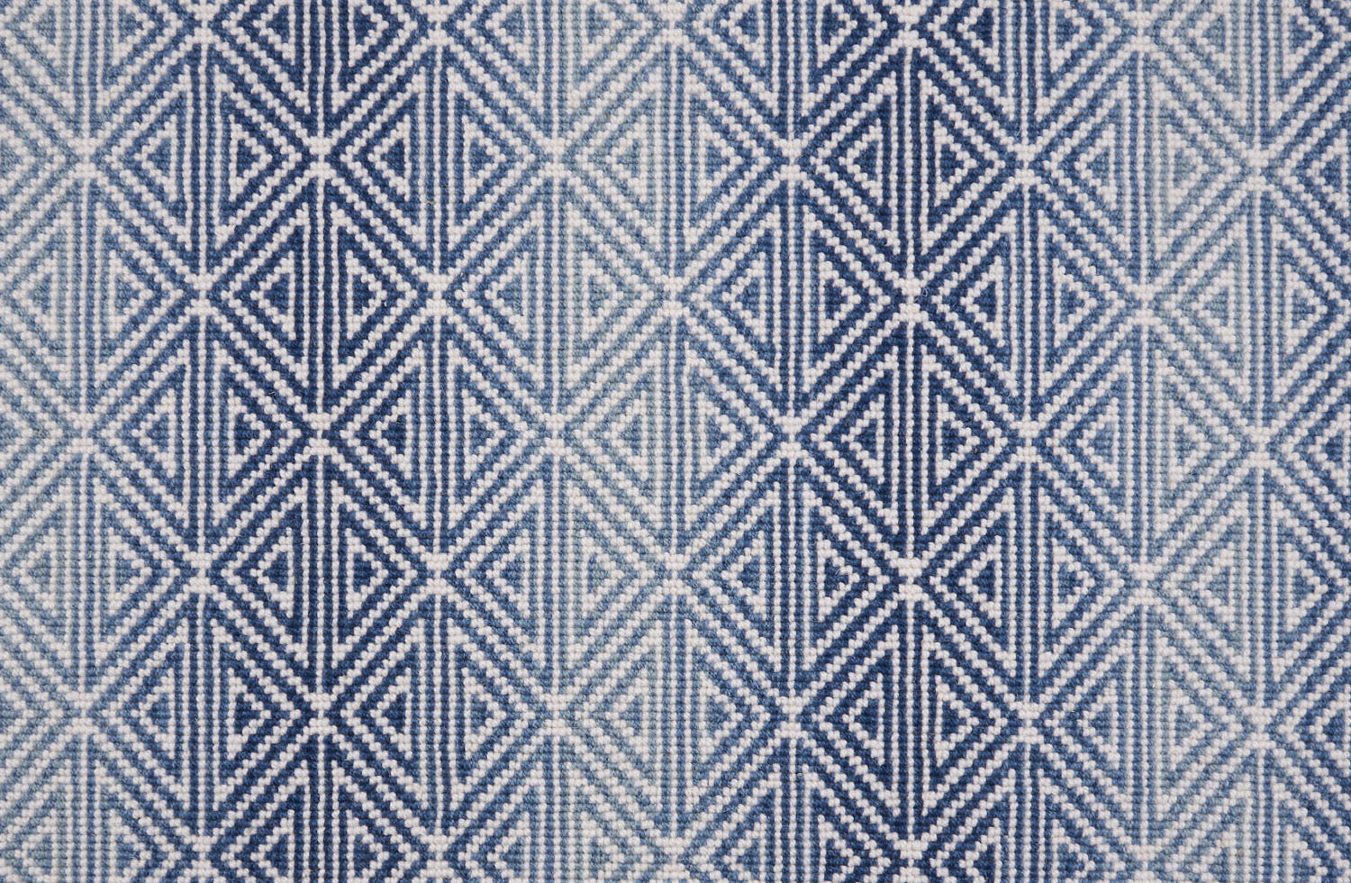 Broadloom carpet with triangle pattern with an ombré background in shades of blue. 