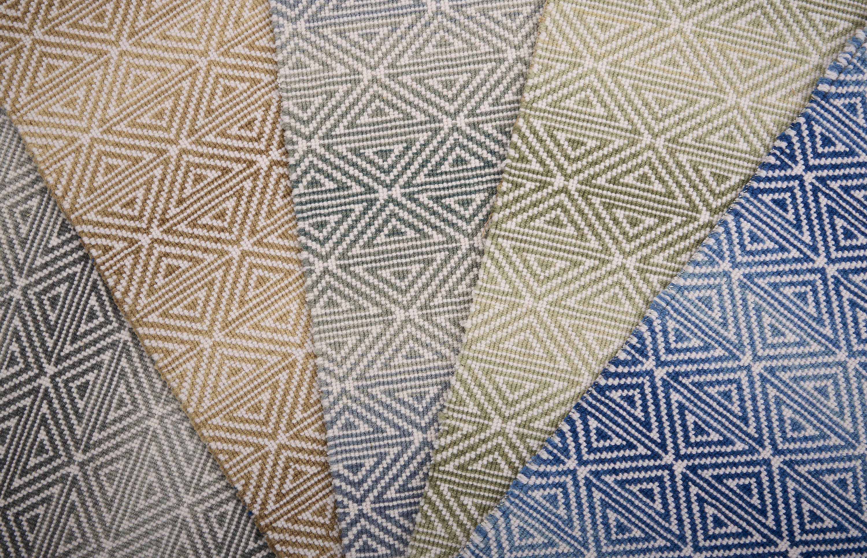 Collection of broadloom carpet swatches with geometric patterns in various colors.