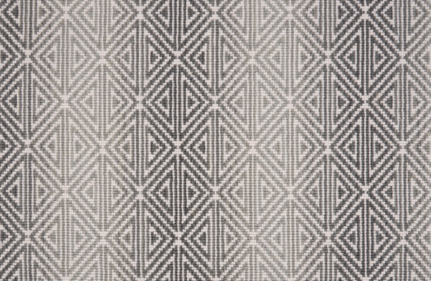 Broadloom carpet with triangle pattern with an ombré background in shades of grey. 