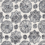 Detail of fabric in a geometric damask print in shades of gray on a cream field.