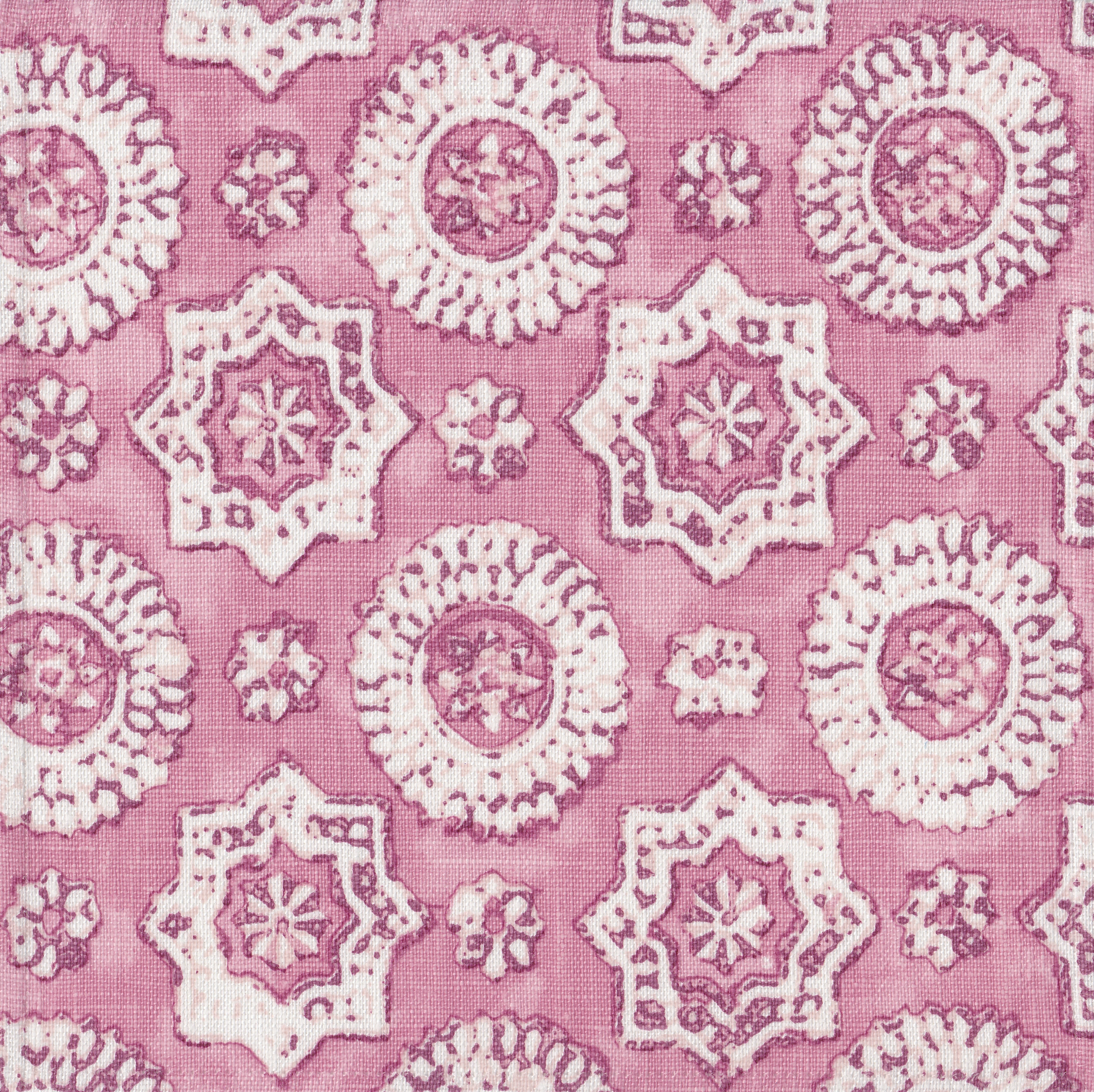 Detail of fabric in a geometric damask print in shades of pink and cream on a pink field.