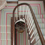 Striped flatweave runner in green pink blue yellow on wood staircase