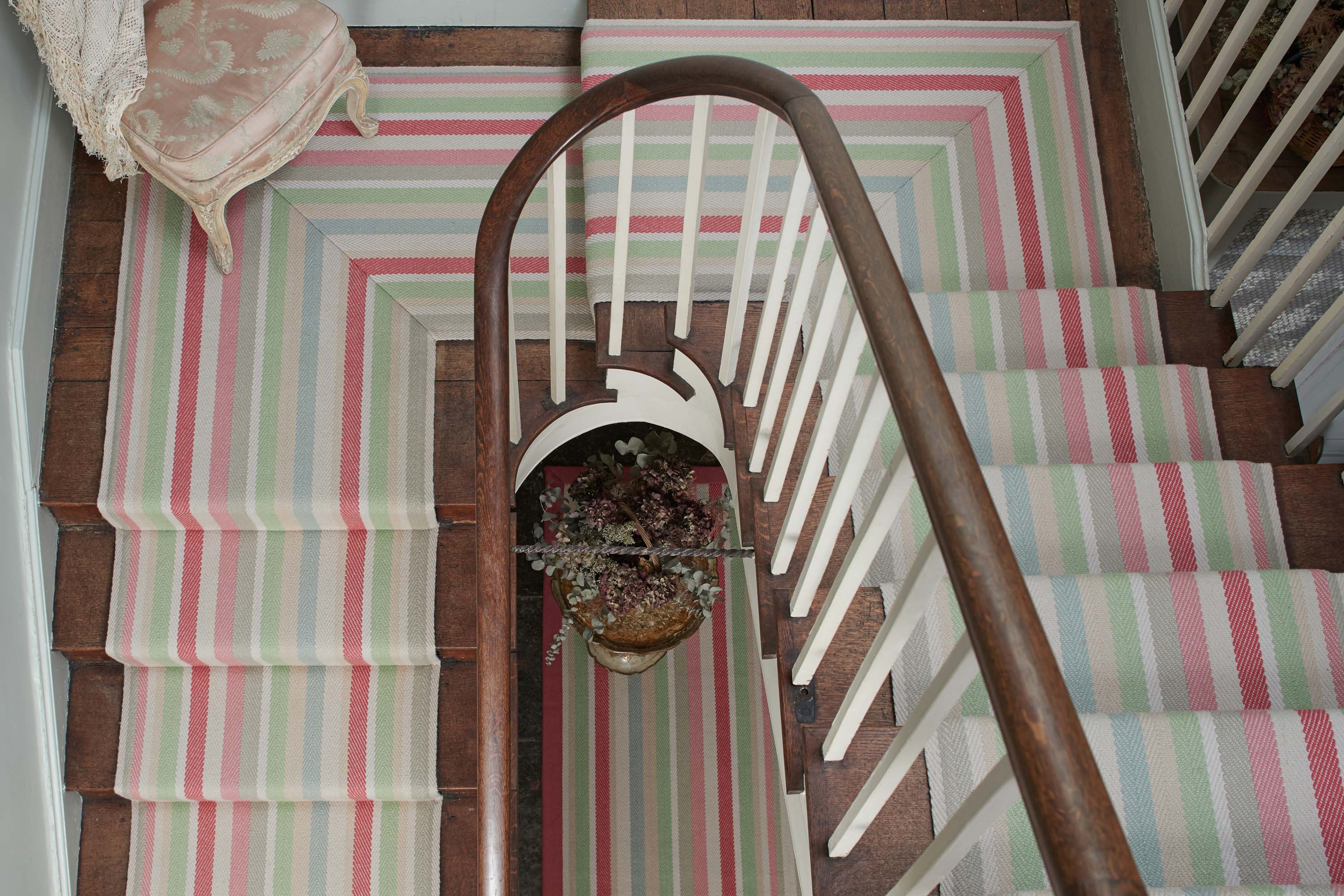 Striped flatweave runner in green pink blue yellow on wood staircase