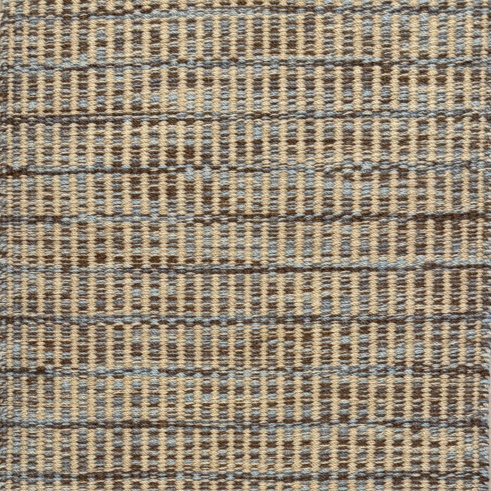 Textured rug with a brown, grey and tan checker pattern