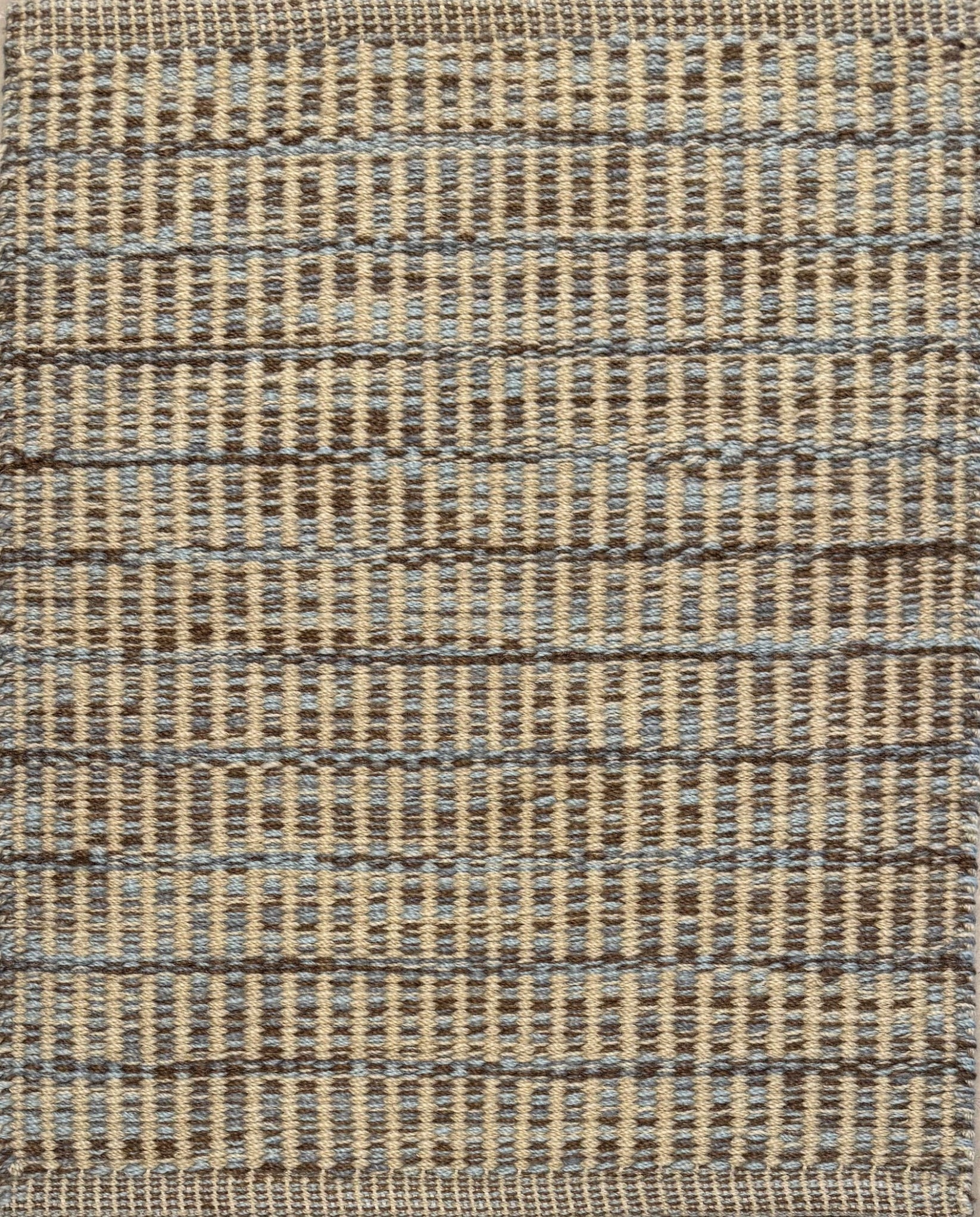 Textured rug with a brown, grey and tan checker pattern