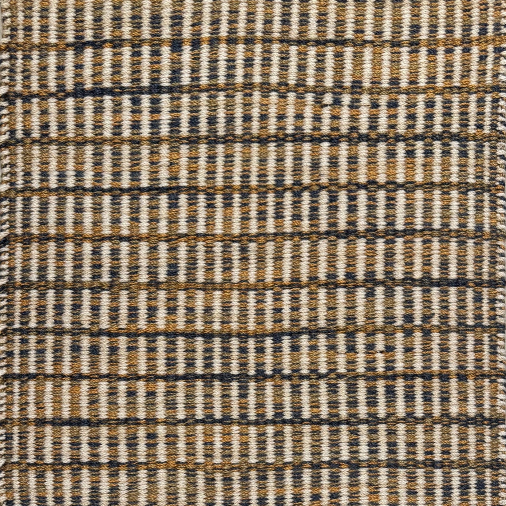 Textured rug with a navy, tan and beige  checker pattern