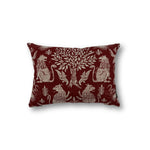 Rectangular throw pillow with a tree at center framed with symetrical lion figures, the back ground is a solid brick red, the motif is a natural linen color. 