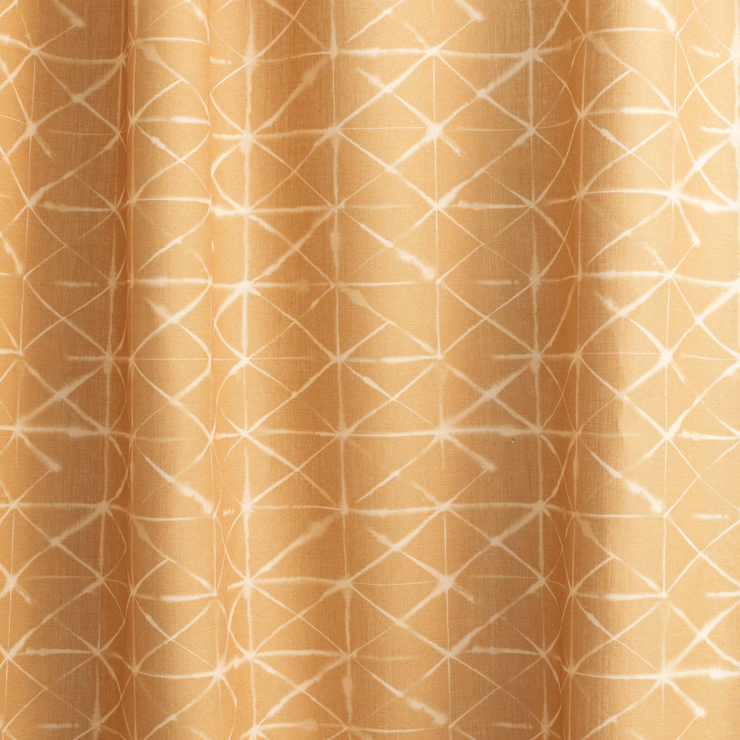 Draped fabric in a mottled lattice print in white on a burnt orange field.