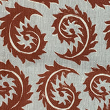 Close-up of fabric in a repeating curved leaf print in white and brown on a gray field.