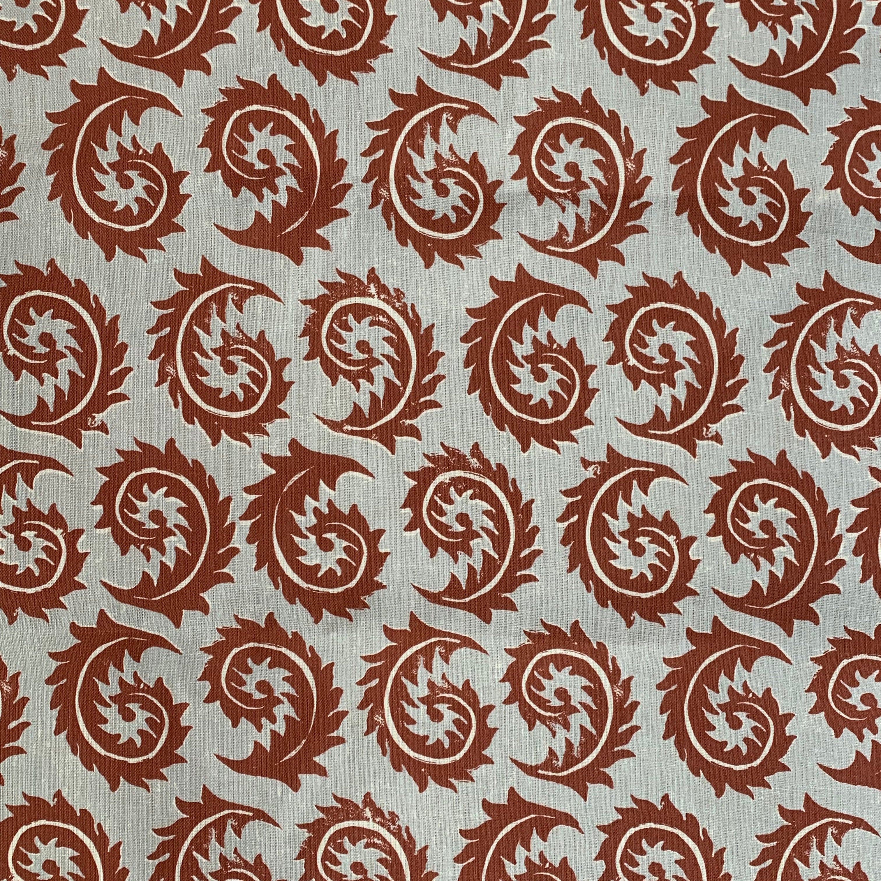 Detail of fabric in a repeating curved leaf print in white and brown on a gray field.