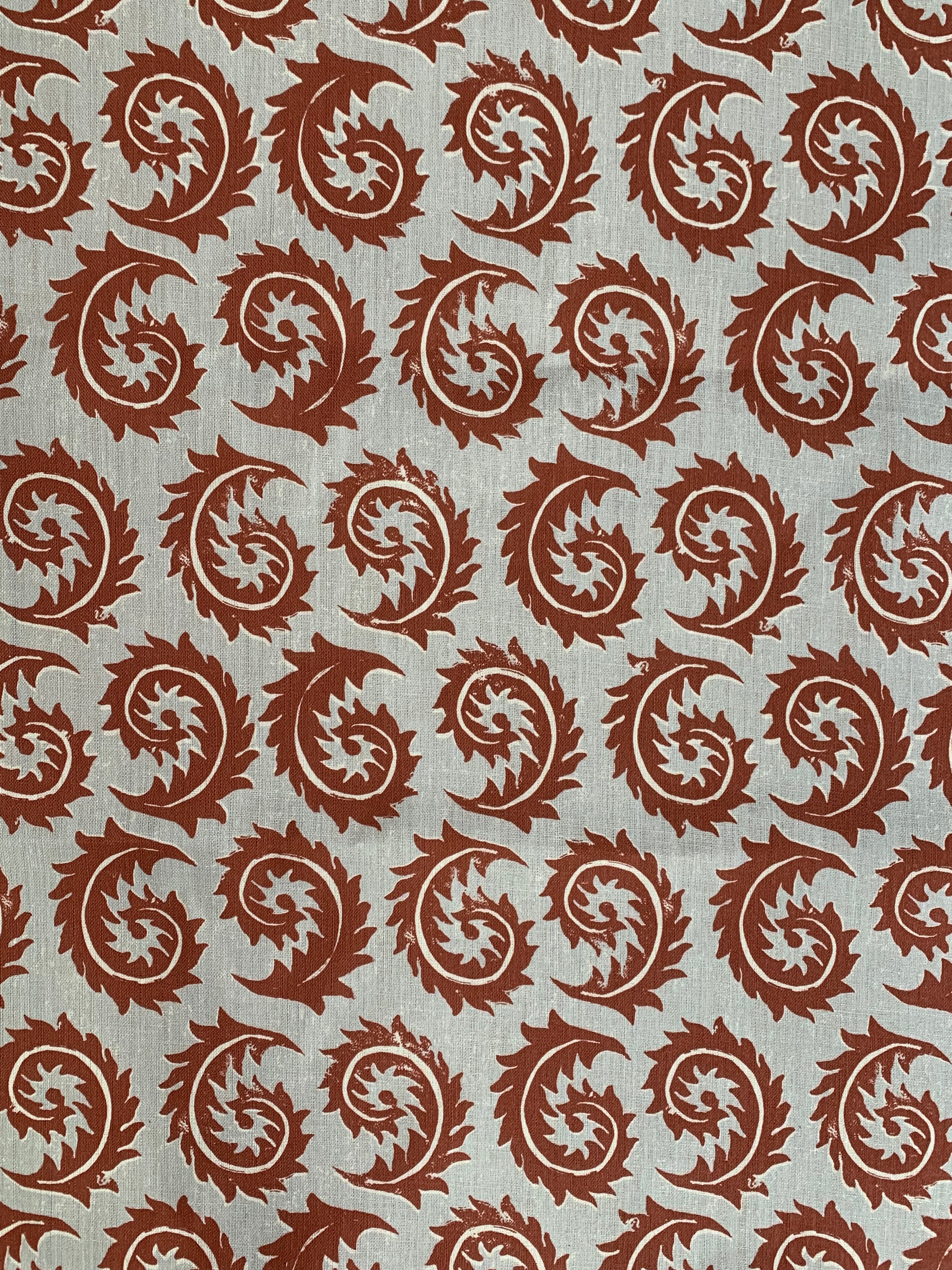 Detail of fabric in a repeating curved leaf print in white and brown on a gray field.