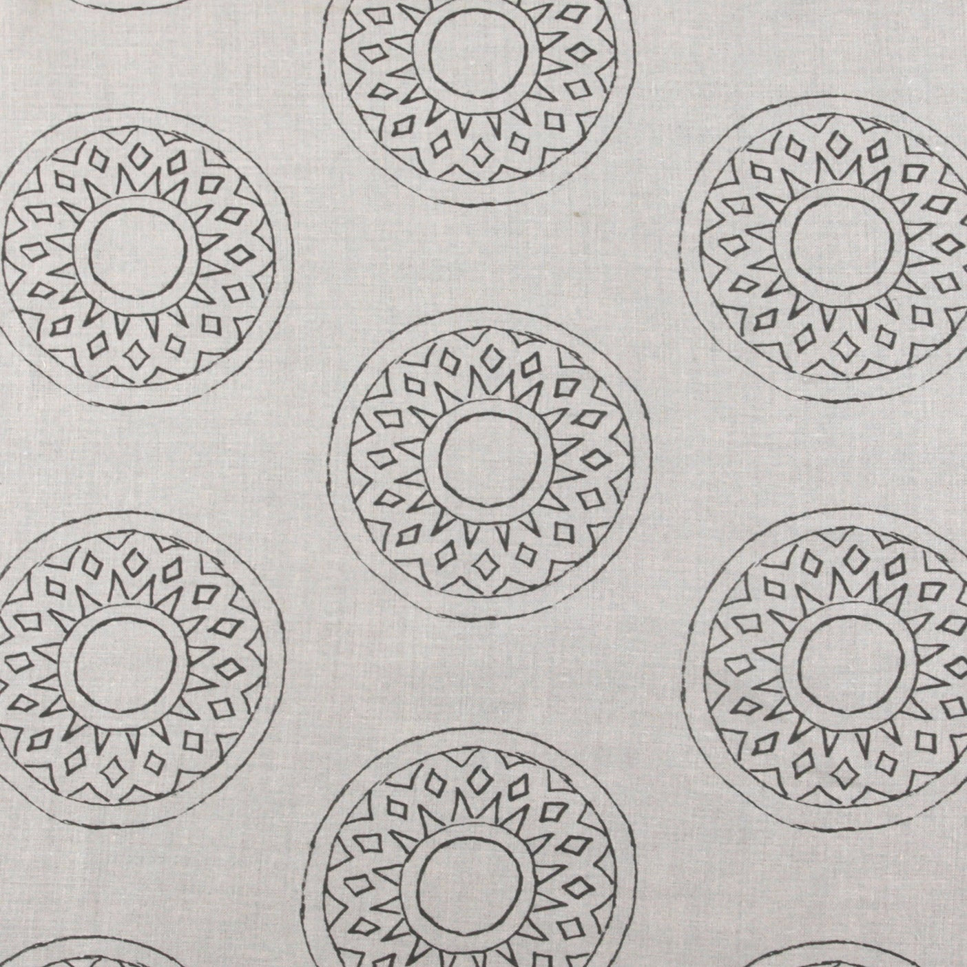 Detail of fabric in a repeating circular geometric print in gray on a greige field.