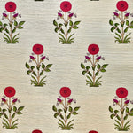 Detail of fabric in a large-scale marigold print in red, purple and green on a cream field.