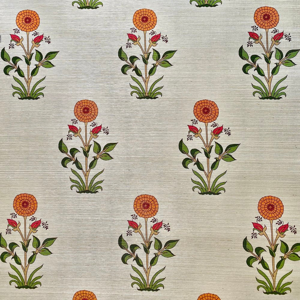 Detail of fabric in a large-scale marigold print in orange, red and green on a tan field.