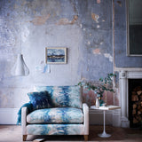 A chabby-chic living space with an armchair upholstered in an abstract paint blot pattern in green, blue and cream.