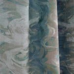 Close-up of draped fabric in an abstract paint blot pattern in shades of green, blue and cream.